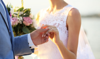 Groom and bride hands on sunset background