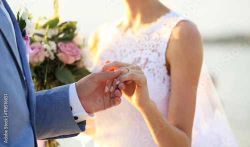 Groom and bride hands on su...