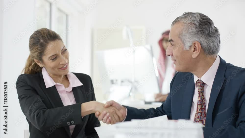 Smiling Western & Arab business people shake hands in meeting Smiling Western & Arab business people shake hands in meeting