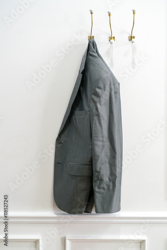 Man's jacket hanging on a coat hanger at a wall
