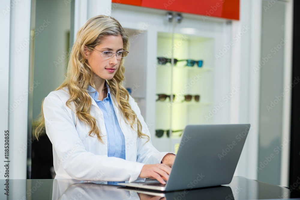 Optometrist using laptop in ophthalmology clinic Optometrist using laptop in ophthalmology clinic