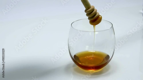 Someone is takinga wooden stick out of a glass and some honey is oozing down. Close-up shot.
 photo