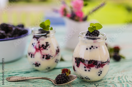 Yogurt with fresh blackberry fruit on wooden table
