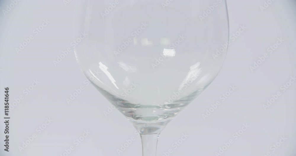 An empty glass is standing on a table and someone starts pouring red wine into it. Close-up shot.
An empty glass is standing on a table and someone starts pouring red wine into it. Close-up shot.