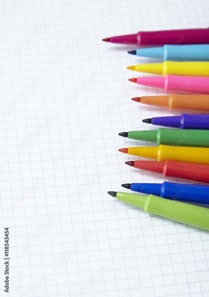 Colorful felt tip pens arranged on a white squared paper background to form a page border Colorful felt tip pens arranged on a white squared paper background to form a page border