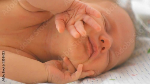 Newborn baby girl stretching herself while sleeping