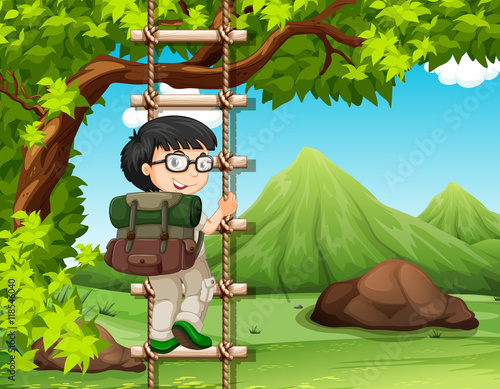 Boy climbing up the wooden ladder in park