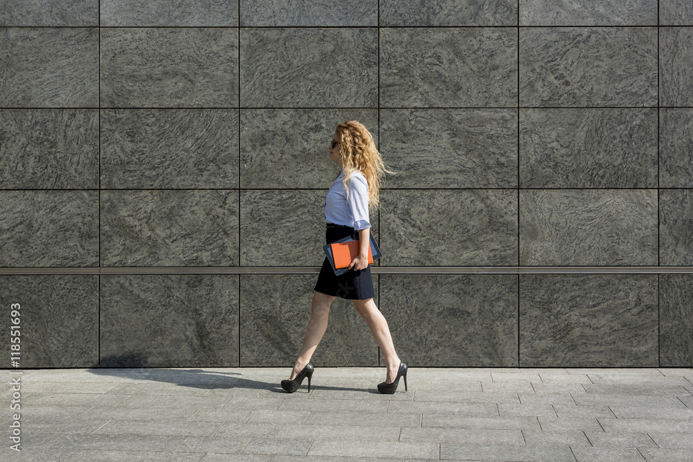 Businesswoman holding book and digital tablet walking outdoors Businesswoman holding book and digital tablet walking outdoors