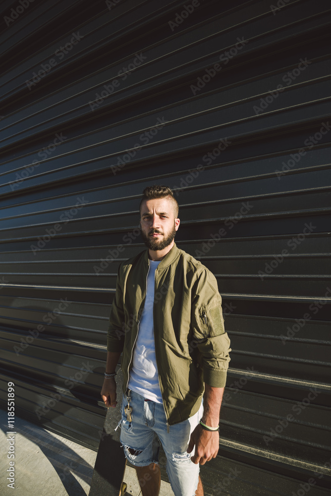 Man with skateboard standing in front of facade