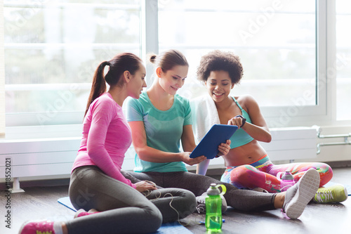 group of happy women with tablet pc in gym