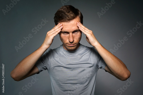 Young man in t-shirt thinking or experiencing headaches.