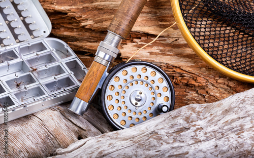 Vintage fly fishing outfit and gear on rocks and wood background