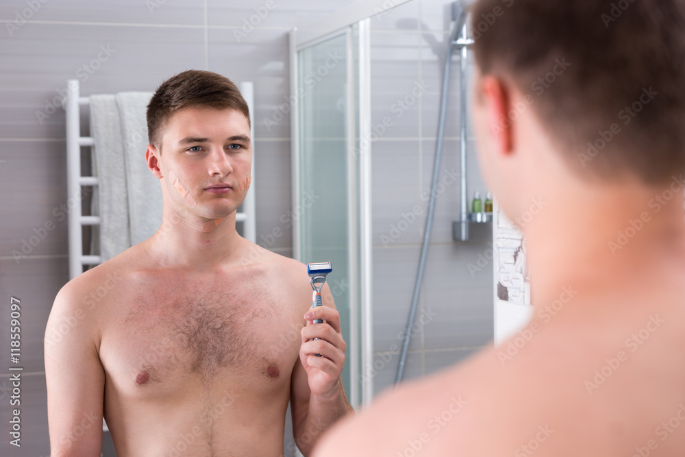 Reflection of a man after bad shaving with bandaids on his face Stock