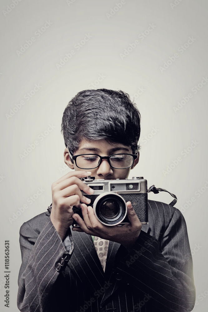 Fototapeta premium Child photographer holding a camera indoor