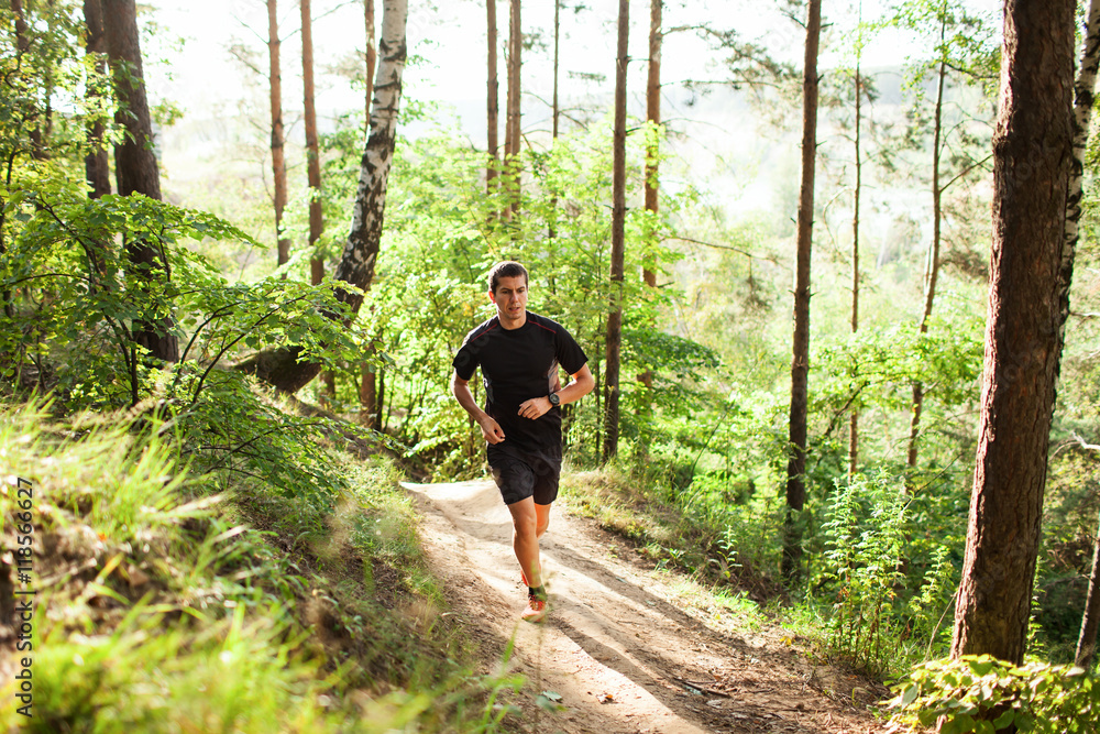 Male athlete runner running on road in forest