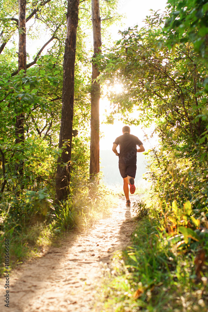 Male athlete runner running on road in forest