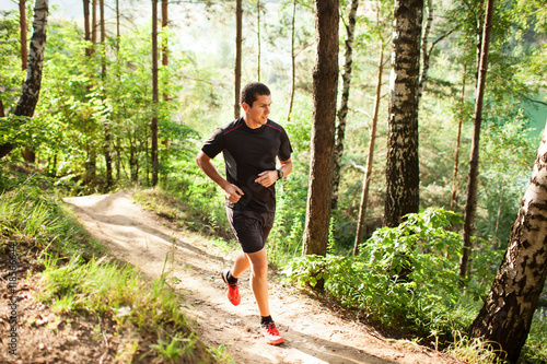 Obraz na płótnie Male athlete runner running on road in forest w salonie