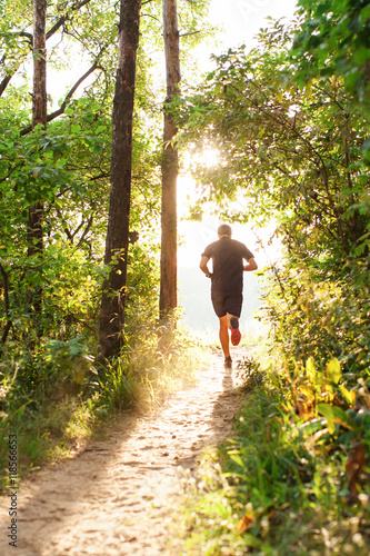 Male athlete runner running on road in forest