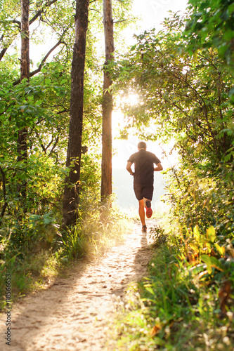 Obraz na płótnie Male athlete runner running on road in forest w salonie