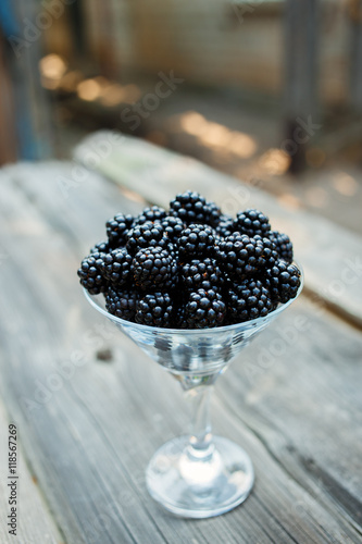 Ripe blackberry in a glass on wooden boards