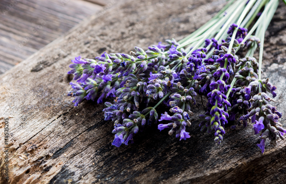 Naklejka premium Wiązka lawendowi kwiaty na drewnianym tle.