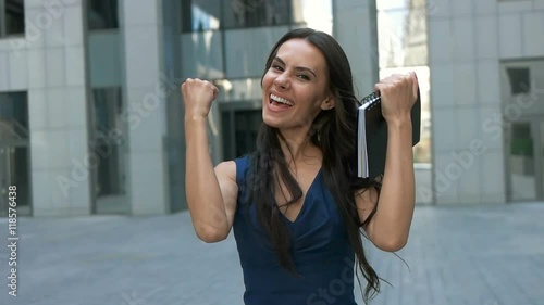 Business success - Celebrating businesswoman walking near the city center high-rises.