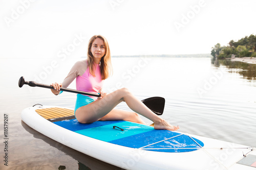 Young woman paddling on sup board © serhiipanin