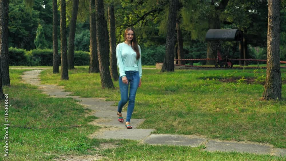 Bright young brunette girl with long hair is the walk in the park and go down the side. Bright young brunette girl with long hair is the walk in the park and go down the side.