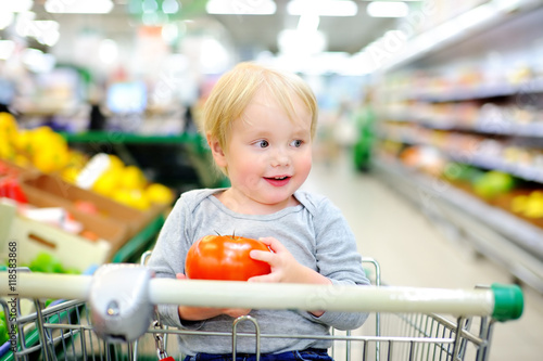 Toddler sitting in the shopping cart in a supermarket