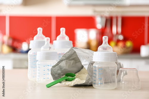 Feeding bottles and baby milk formula on kitchen background