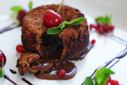 Delicious fondant with cherry and red currant on plate, closeup