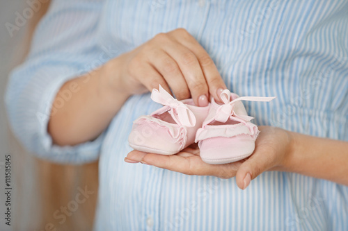 Pregnant woman with baby bootees at home
