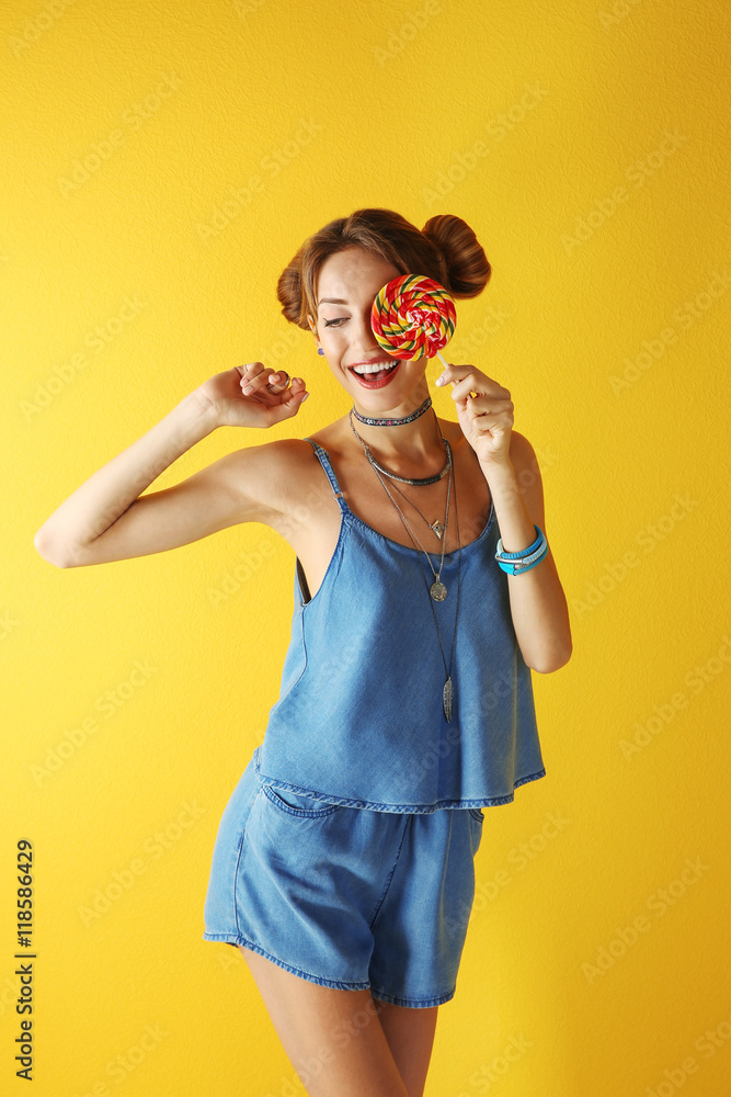 Beautiful girl with candy on yellow background Beautiful girl with candy on yellow background