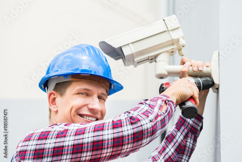 Male Technician Installing Camera On Wall