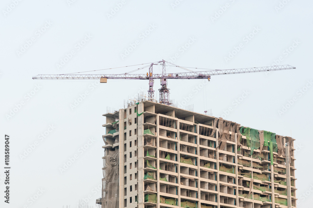 Building site with high-rise block under construction in an urban environment dominated by a large industrial crane Building site with high-rise block under construction in an urban environment dominated by a large industrial crane