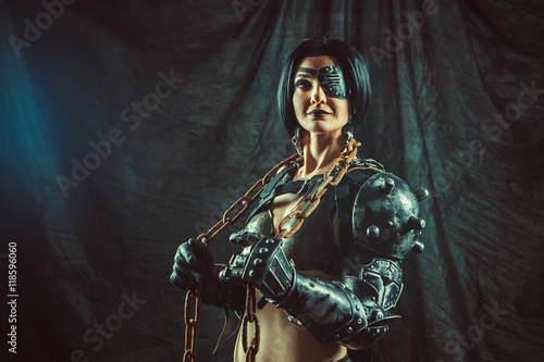Powerful steam punk woman in metal lingerie is holding a chain.