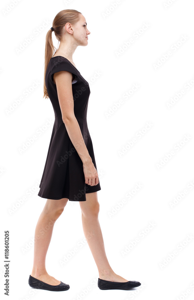 Fototapeta premium back view of walking woman. beautiful girl in motion. backside view of person. Rear view people collection. Isolated over white background. Blonde in a short black dress out of the frame.