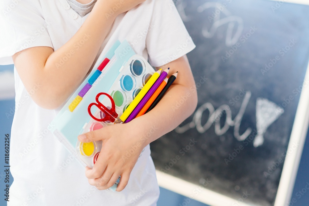Happy seven years old boy holding his school supplies. Happy seven years old boy holding his school supplies.