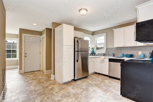 Kitchen room interior with white cabinets and tile floor.