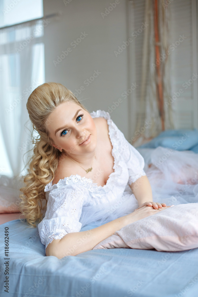 Radiant blonde woman with deep blue eyes lies on the bed Radiant blonde woman with deep blue eyes lies on the bed