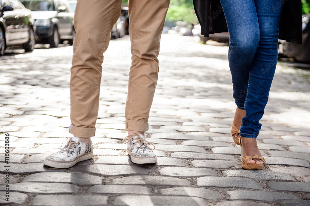 Close up of couple's legs in keds standing at street. Close up of couple's legs in keds standing at street.
