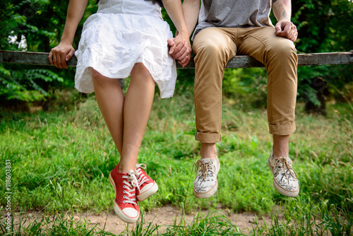 Close up of couple in keds sitting on bench. photo