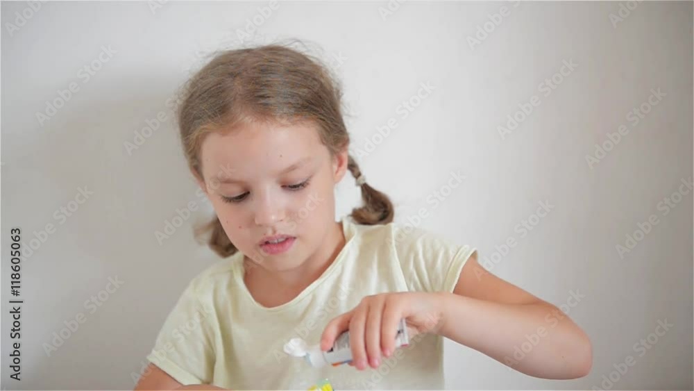 Little girl in bathroom putting a toothpaste on toothbrush Little girl in bathroom putting a toothpaste on toothbrush