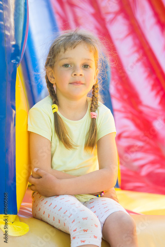 Five-year girl naprygalis on a large inflatable trampoline sat down to rest