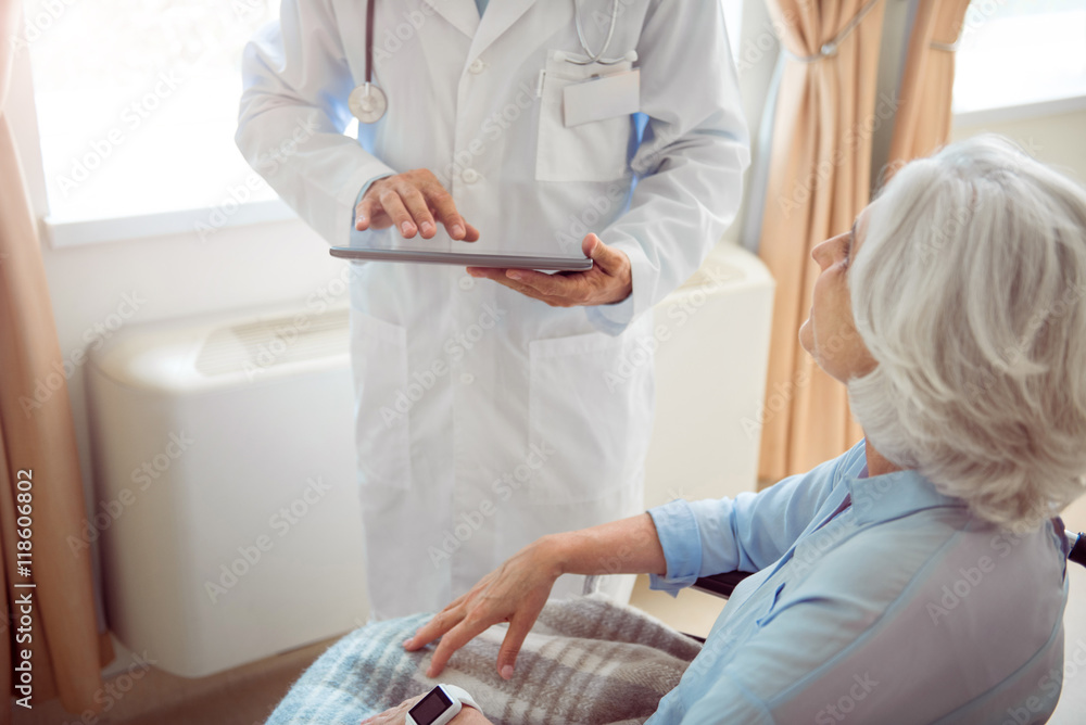 Fototapeta premium Senior woman in wheelchair with doctor