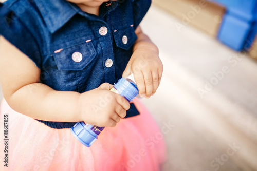 Look from above at tiny little girl holding a bottle with soap b