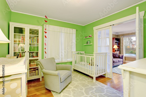 Kids room in white and green tones with beige armchair