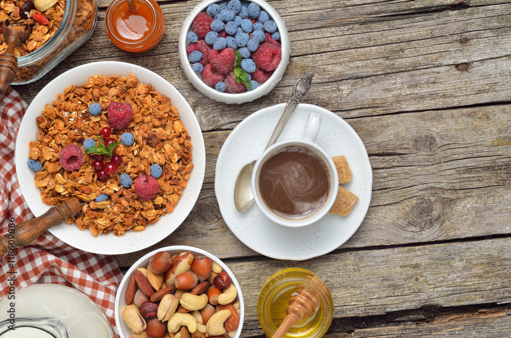 Breakfast table - berries, homemade granola, milk, dried fruits, nuts on wooden background. Copyspace background.Top view.