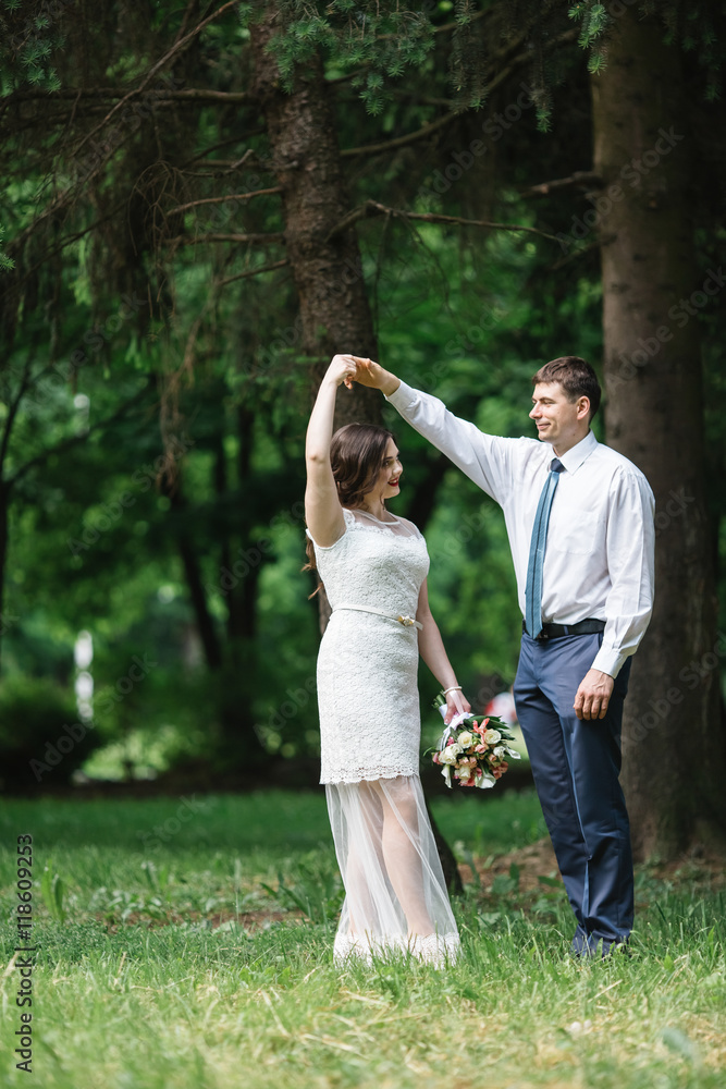 Groom in blue trousers whirls stunning bride on the green lawn