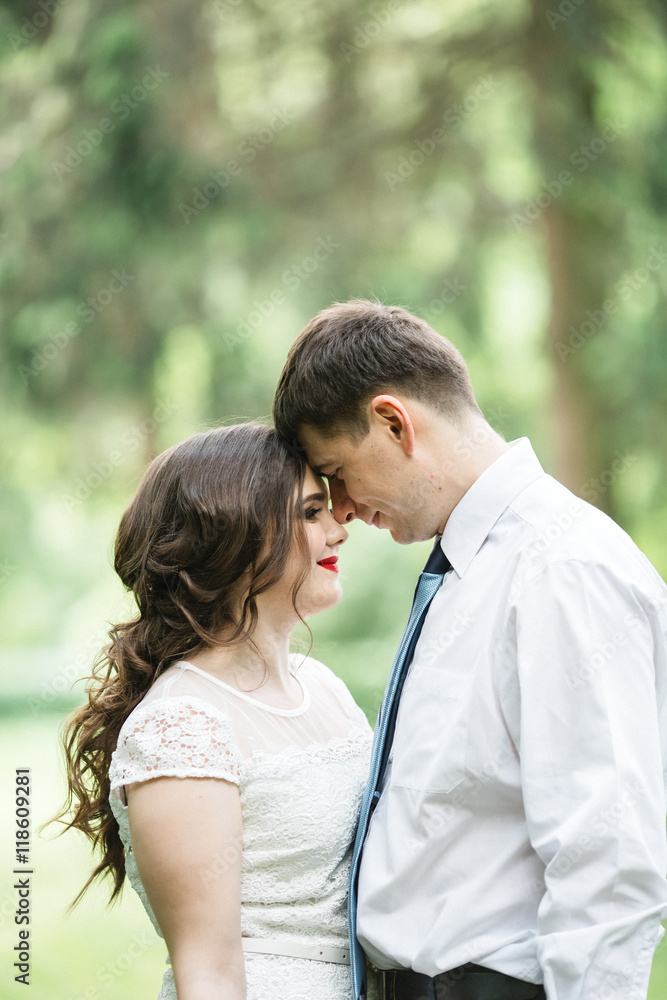 Bride and groom lean to each other foreheads while standing in t Bride and groom lean to each other foreheads while standing in t